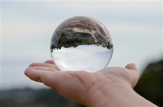 A man holds an orb which bends and changes an image.