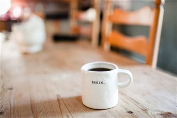 A lone coffee cup with "Begin." Written on it. Photo by Danielle MacInnes